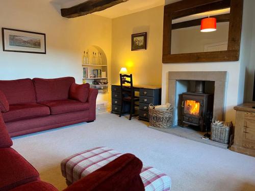 a living room with a red couch and a fireplace at Stunning 4 bed Grade house in the Lake District in Wigton