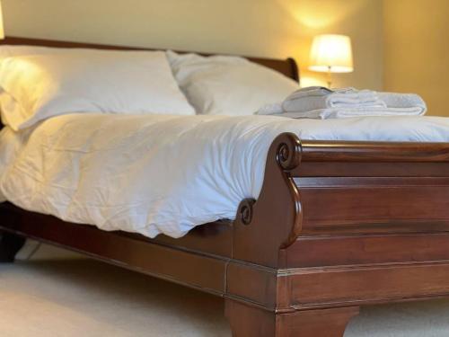 a bed with white sheets and a wooden frame at Stunning 4 bed Grade house in the Lake District in Wigton