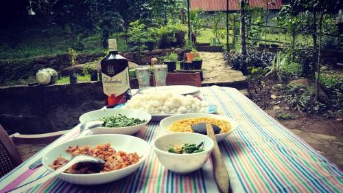 una mesa con tazones de comida y una botella de vino en Riverston Nature Villa, en Rattota
