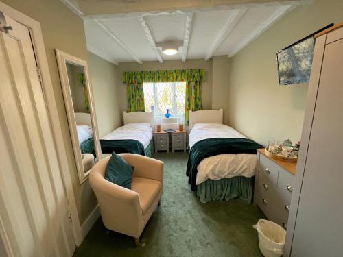 a bedroom with two beds and a chair and a mirror at Pentre Cerrig Country House in Llanferres