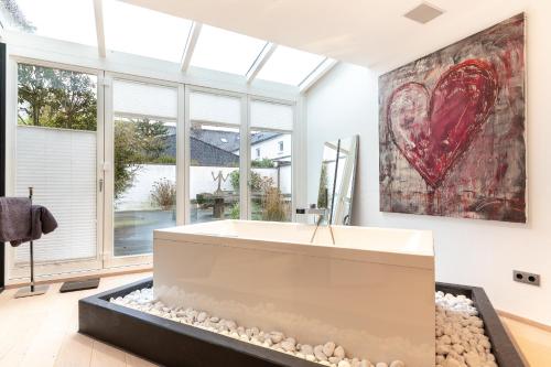 a bathroom with a bath tub and a large painting of a heart at James Home in Kampen