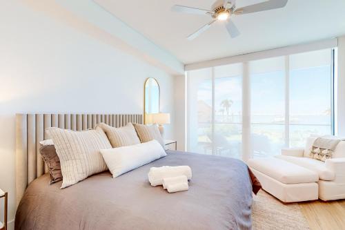 a white bedroom with a large bed and a chair at Harbor Island Villa Unit 205 in Melbourne Beach