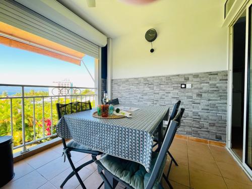 a dining room with a table and chairs and a balcony at Appartement vue mer, piscine, dans quartier prisé de Gosier in Le Gosier