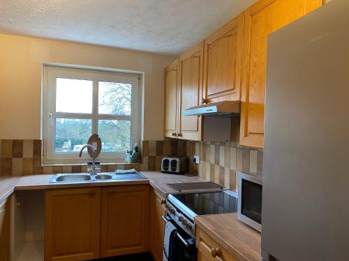 a kitchen with wooden cabinets and a sink and a window at River Penthouse Apartment In The Heart of in Saint Neots