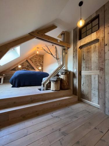 een slaapkamer met een bed en een houten vloer bij Vakantiewoning met sauna & hottub en zwempoel op Natuurterrein in Heuvelland