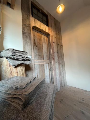 a room with a wooden door and a bed at Vakantiewoning op Natuurterrein t Heuvelhof met optioneel hottub en sauna in Heuvelland