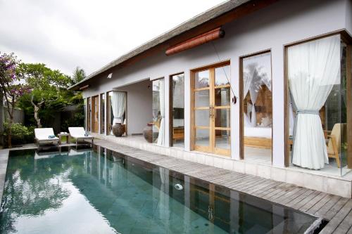 a house with a swimming pool in front of it at Villa Kayu Lama in Ubud