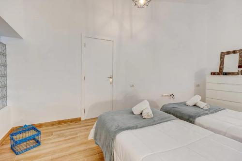 two beds in a room with white walls and wood floors at Apartamento Caleta Interian in Santa Cruz de Tenerife