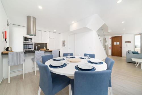 a dining room and kitchen with a white table and blue chairs at Villa Atlântico - By SCH in Salir de Porto