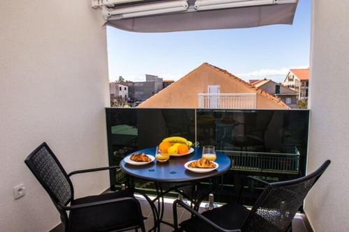 a table with plates of food on a balcony at Apartments Zdeslav in Rogoznica