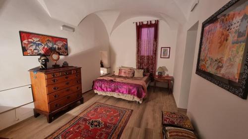 a bedroom with a bed and a dresser and a rug at Beautifully restored romantic apartment in the centre of historic Dolcedo in Dolcedo