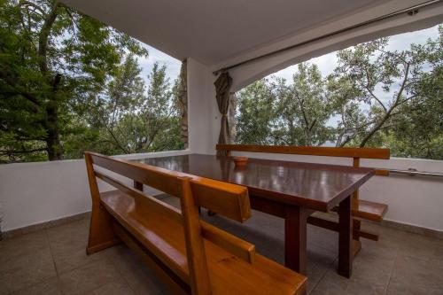 a dining room with a table and benches on a balcony at House Dino in Tkon