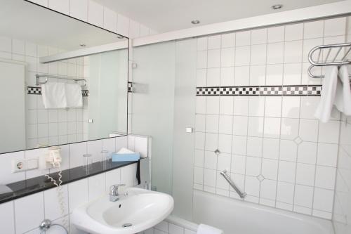 uma casa de banho branca com um lavatório e um chuveiro em Memphis Hotel em Frankfurt