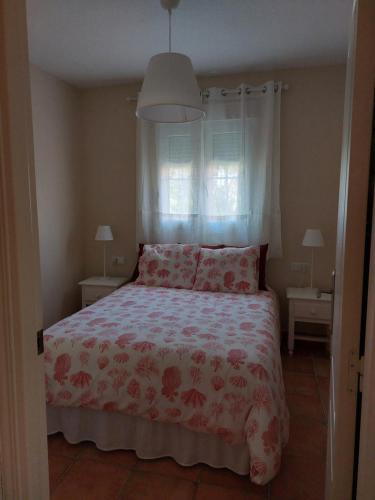 - une chambre dotée d'un lit avec un couvre-lit floral dans l'établissement Aldea Playa Golf 2 dormitorios, à Huelva