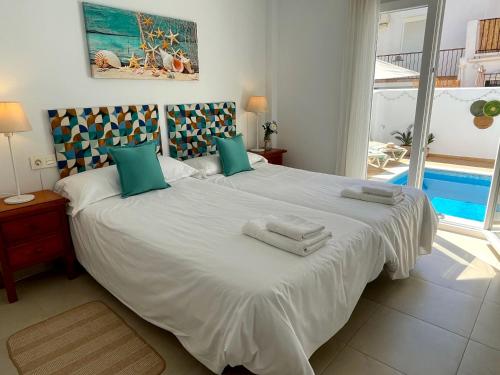 a bedroom with a large white bed with towels on it at Nerja Paradise Rentals - Villa Zafiro in Nerja