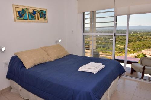 1 dormitorio con cama azul y ventana grande en Departamento Pircas in 