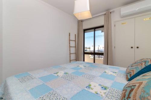 een slaapkamer met een bed met een blauwe en witte quilt bij Beco Da Hortinha in Ferragudo