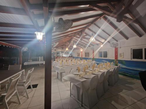 a banquet hall with white tables and white chairs at Les Villas de Boisvin in Le Moule