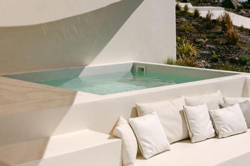 a plunge pool in a white house with pillows at Le Cote Oia in Oia