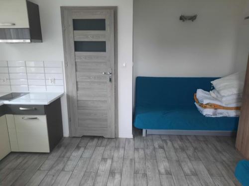 a small kitchen with a blue couch in a room at Pokoje gościnne Promenada in Sarbinowo