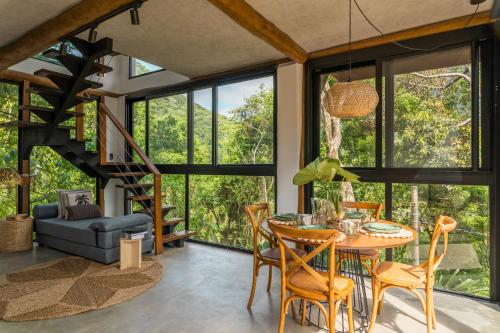 a living room with a table and chairs and a staircase at Casa Waimea in Ubatuba
