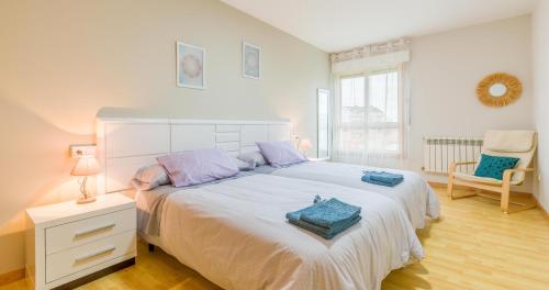 a bedroom with a large white bed and a chair at Casa Naseiro in Melide