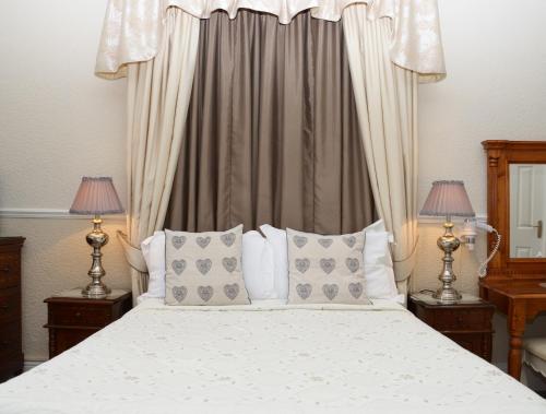 a bedroom with a white bed with pillows and two lamps at The Cumberland in Llandudno