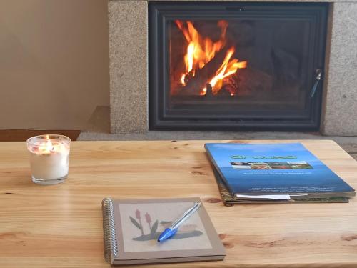 a table with a laptop and a candle and a fireplace at Casa Naseiro in Melide