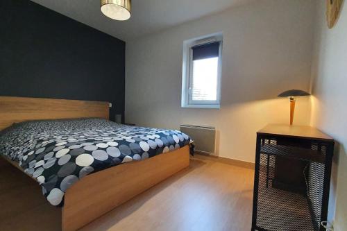 een slaapkamer met een bed, een tafel en een raam bij Résidence Escale Océane T2 42 m2 à 500 m de la Plage in Capbreton