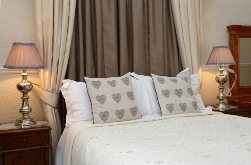 a bedroom with a white bed with pillows and two lamps at The Cumberland in Llandudno