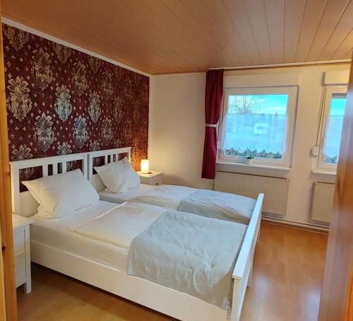a bedroom with a white bed and two windows at Pension ZUM LINDENWALD Colbitz in Kolbitz