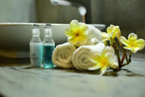 a bathroom with towels and two bottles of water and flowers at Elephant Trail in Udawalawe