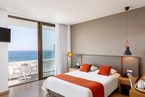 a bedroom with a large bed and a view of the ocean at Crystal Springs Beach Hotel in Protaras