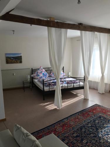 1 dormitorio con 1 cama con cortinas y alfombra en Ferienwohnung Brauneberger Juffer im Alten Pfarrhaus, en Brauneberg