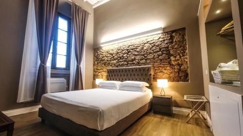 ein Schlafzimmer mit einem Bett und einer Steinmauer in der Unterkunft Il Borgo Your Luxury Suites in Nettuno
