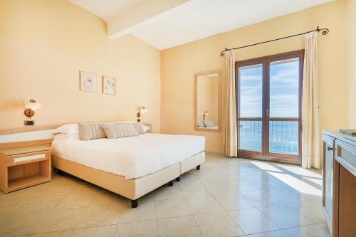 sypialnia z łóżkiem i dużym oknem w obiekcie Hotel La Baja w mieście Santa Caterina