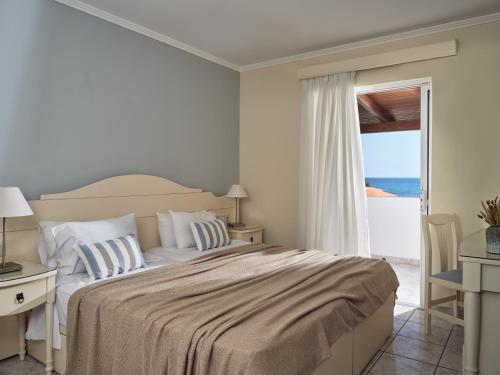 a bedroom with a bed with a view of the ocean at Windmill Hotel in Argasi