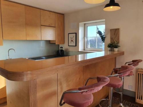 a kitchen with a counter with two pink stools at The Milltown Apartment in Dublin