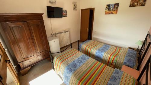 a bedroom with two beds and a cabinet and a tv at Agriturismo Da Pietro in Pomarance