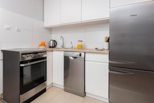 uma cozinha com fogão de aço inoxidável e frigorífico em Śródmieście Gdynia Studio Zygmunta Augusta by Renters em Gdynia