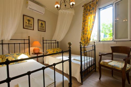 Duas camas num quarto com uma janela e uma cadeira. em Casa Paleopolis em Corfu Town