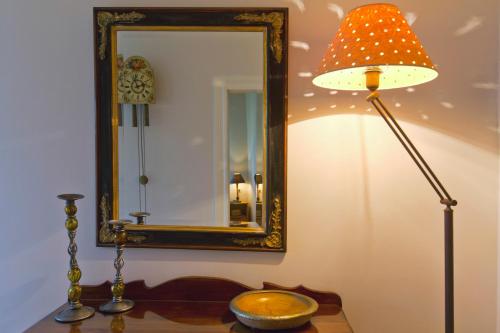 Ein Tisch mit einer Lampe und einem Spiegel an einer Wand in der Unterkunft Casa Paleopolis in Korfu-Stadt