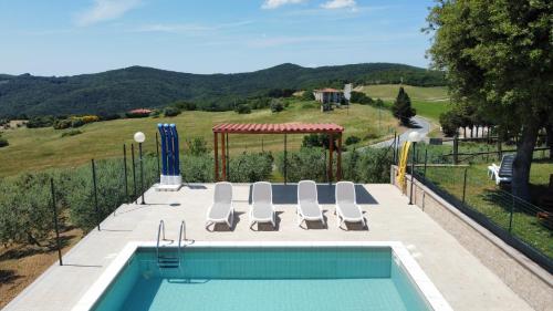 a swimming pool with chairs and a gazebo at Agriturismo Da Pietro in Pomarance