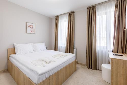 a bedroom with a bed with white sheets and a window at Баня Аква Ризорт in Banya