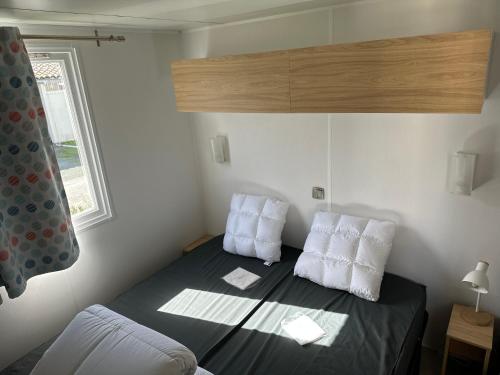 a small bedroom with a bed with two pillows at mobil home 6 places tout confort in Saint-Georges-de-Didonne