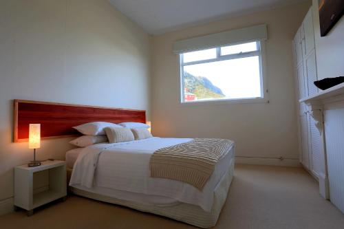 a white bedroom with a bed and a window at @ the beach & not quite @ the beach Holiday Cottages - Stanley in Stanley