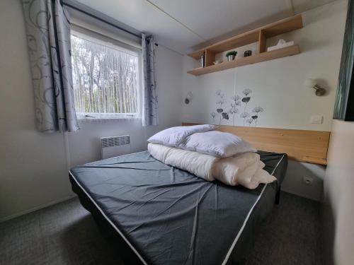 a bedroom with a bed with pillows and a window at Beau Mobil home 64 in Saint-Jean-de-Monts