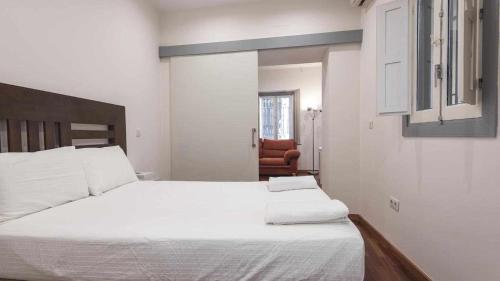 um quarto com uma grande cama branca e uma cadeira laranja em La Casa de la Plata by Toledo AP em Toledo