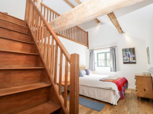 a bedroom with a bed and a wooden staircase at Owl Barn in Leominster