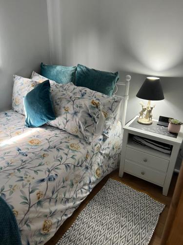a bedroom with a bed and a night stand with a lamp at Kabin in the woods in Llandybie
